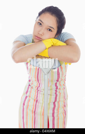 Fronçant woman leaning on mop Banque D'Images