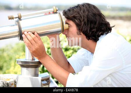 Homme regardant à travers un télescope Banque D'Images