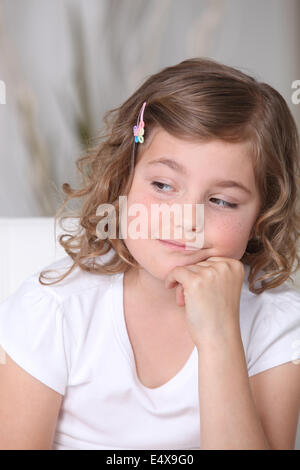 Petite fille assise sur le canapé Banque D'Images