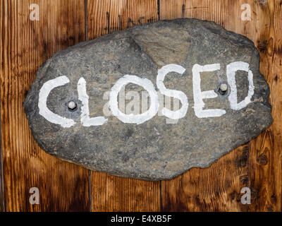 Le signe 'fermé', écrit sur une pierre ovale, cloué sur une porte en bois Banque D'Images