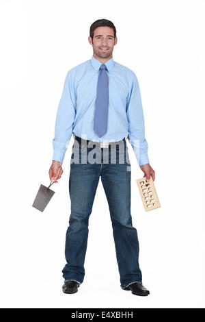 La tenue de l'entrepreneur et à la truelle une brique Banque D'Images