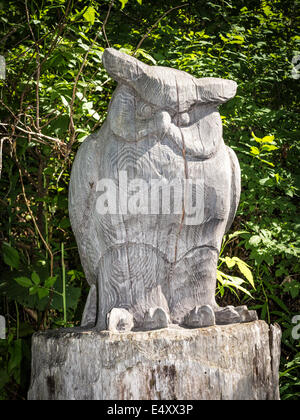 Une sculpture en bois d'un hibou, taillée dans un tronc d'arbre, le long d'un sentier nature en Suisse Banque D'Images