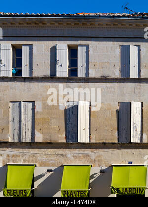 Vue sur la place d'un immeuble typique à Pons France avec des volets en bois au-dessus d'auvents verts appartenant à un magasin qui vend des fleurs Banque D'Images