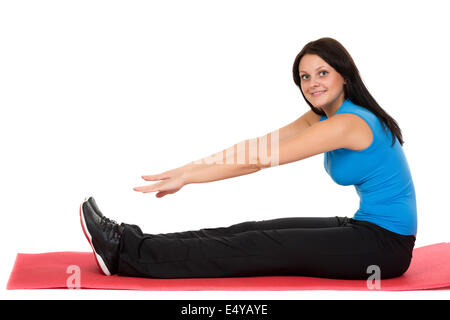 Belle jeune fille assise sur un tapis de yoga Banque D'Images