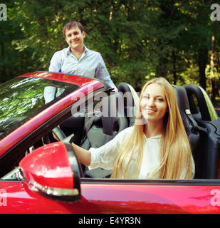 Jeune couple heureux près de la voiture rouge Banque D'Images