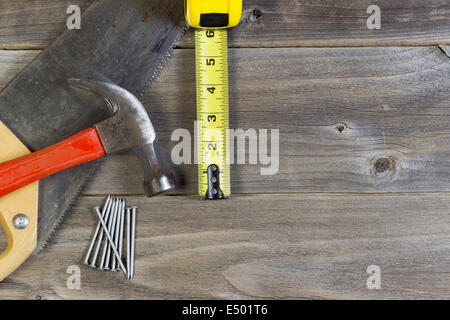Vue du dessus de l'accueil les outils de réparation composé de scie à bois, marteau, clous, et ruban de mesure sur les planches de bois rustique Banque D'Images