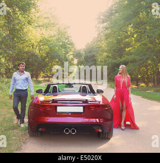 Jeune couple heureux près de la voiture rouge Banque D'Images