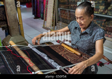 Bali, Indonésie. Femme tissant avec la gaine de sangle pour tisser Geringsing chiffon, une spécialité de Tenganan Village. Banque D'Images