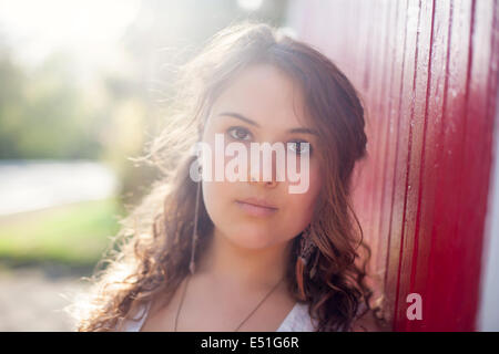 Portrait of young woman leaning on wooden wall Banque D'Images