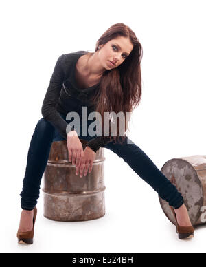 Jeune fille en jeans assis sur un baril de fer Banque D'Images