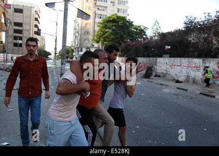 La ville de Gaza, Territoires palestiniens. 18 juillet, 2014. Gaza, bande de Gaza, Territoires palestiniens. 18 juillet, 2014. Les hommes palestiniens aider un journaliste local qui s'est blessé au cours d'un bombardement israélien sur un bâtiment de bureaux hébergeant plusieurs médias dans la ville de Gaza, 18 juillet 2014. Credit : ZUMA Press, Inc./Alamy Live News Banque D'Images