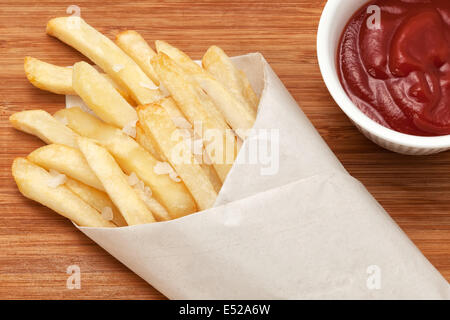 Les frites dans du papier d'emballage avec du ketchup Banque D'Images