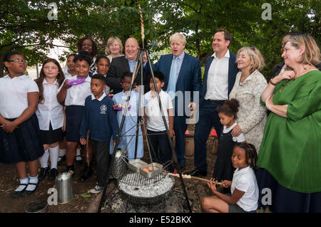 Lambeth, London, UK, 18 juillet 2014. Boris Johnson, Maire de Londres, et Henry Dimbleby, fondateur de Leon restaurants et Rosie Boycott, Président de la London Food Administration, visiter l'école primaire Christ Church, Lambeth pour le petit déjeuner, la promotion des aliments plus sains. L'école primaire Christ Church a une approche novatrice à l'alimentation l'éducation : le maire a rencontré les élèves, les parents et les enseignants sur une visite de l'école l'apprentissage en plein air de domaines, y compris un feu de camping où le pain était cuit par les élèves et un four à pizza où un petit-déjeuner sain était cuit. Crédit : Stephen Chung/Alamy Live News Banque D'Images