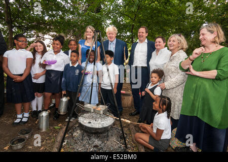 Lambeth, London, UK, 18 juillet 2014. Boris Johnson, Maire de Londres, et Henry Dimbleby, fondateur de Leon restaurants et Rosie Boycott, Président de la London Food Administration, visiter l'école primaire Christ Church, Lambeth pour le petit déjeuner, la promotion des aliments plus sains. L'école primaire Christ Church a une approche novatrice à l'alimentation l'éducation : le maire a rencontré les élèves, les parents et les enseignants sur une visite de l'école l'apprentissage en plein air de domaines, y compris un feu de camping où le pain était cuit par les élèves et un four à pizza où un petit-déjeuner sain était cuit. Crédit : Stephen Chung/Alamy Live News Banque D'Images