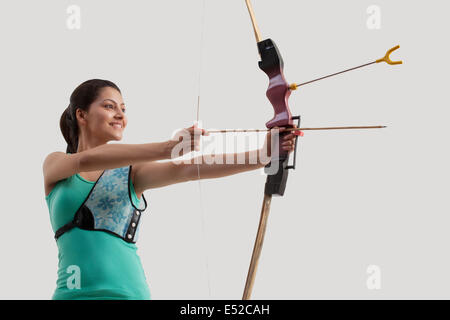 Young woman practicing archery isolé sur fond gris Banque D'Images