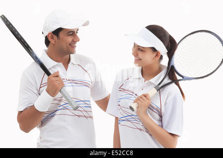 Heureux les joueurs de tennis à l'un l'autre tout en maintenant isolé sur fond blanc Raquettes Banque D'Images