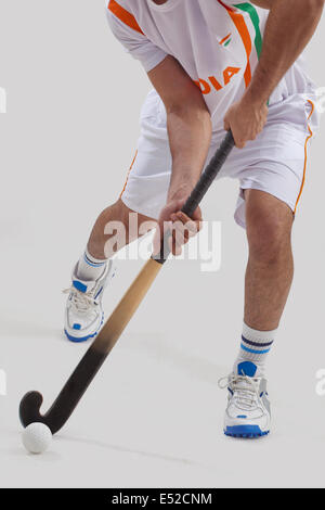 La section basse de l'homme jouant au hockey sur fond gris isolé Banque D'Images