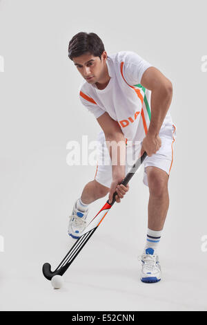 Young man playing field hockey sur fond gris isolé Banque D'Images