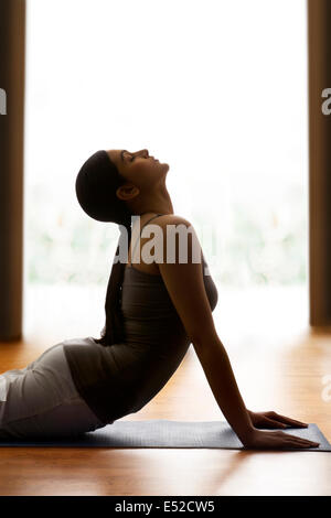 Photo de profil young woman doing yoga salutation 'sun' sur tapis Banque D'Images