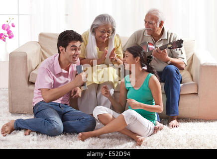 Grand-père joue de la guitare avec grand-mère et petits enfants chanter Banque D'Images