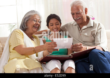 Petite-fille regardant un album photo avec ses grands-parents Banque D'Images