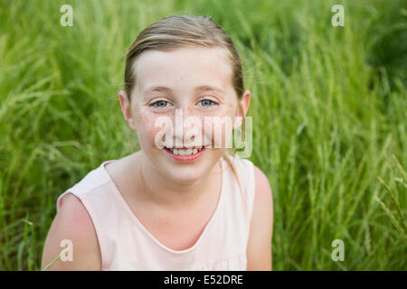 Une jeune fille souriant, assis sur le sol. Banque D'Images