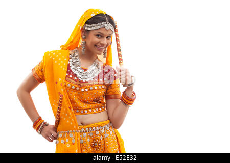 Portrait of happy young woman wearing choli et dupatta avec dandiyas isolated over white background Banque D'Images