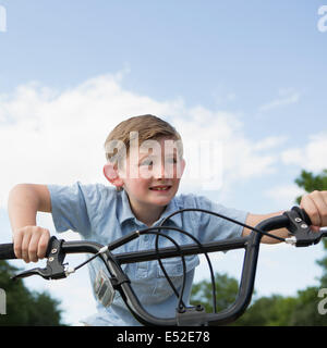 Un jeune garçon se penchant sur le guidon d'un vélo. Banque D'Images