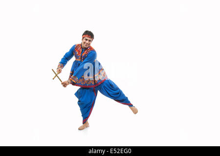 Portrait of happy young man in traditional porter exécution de Dandiya Rass sur fond blanc Banque D'Images