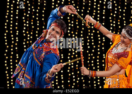 Portrait of young man performing Dandiya Rass avec femme contre l'éclairage au néon Banque D'Images