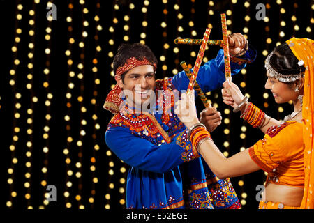 Jeune homme l'exécution de Dandiya Rass avec femme contre l'éclairage au néon Banque D'Images