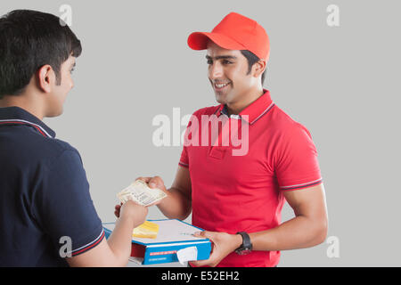 Jeune homme livraison pizza livraison au client sur fond gris Banque D'Images