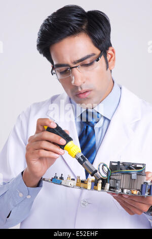 Jeune homme technicien travaillant sur la machine la partie sur fond gris Banque D'Images