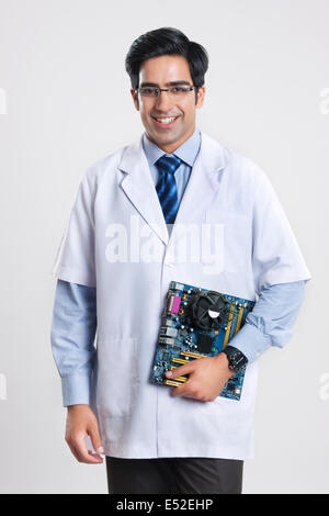 Portrait of male technician holding machine partie contre l'arrière-plan gris Banque D'Images