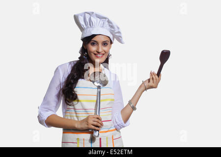 Portrait d'une femme chef de cuisine avec ustensiles de cuisine Banque D'Images