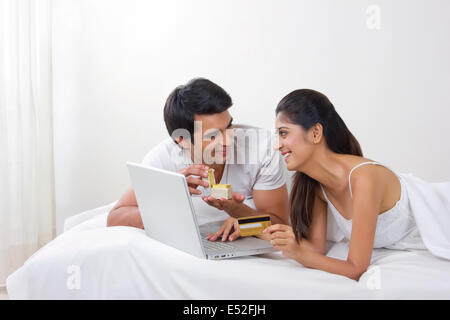 Jeune homme bague d'ouverture fort avec woman shopping online with credit card in bed Banque D'Images