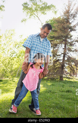 Un jeune enfant dans une robe rose avec ses pieds sur les pieds de son père. Banque D'Images