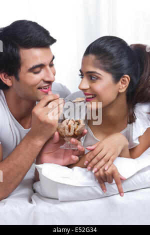 Jeune homme aimant femme alimentation glace au chocolat dans la chambre Banque D'Images