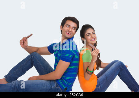 Vue latérale du jeune couple eating ice cream bars over white background Banque D'Images