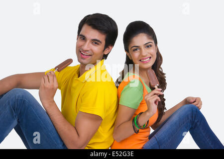 Portrait de beau jeune couple eating ice-cream bars over white background Banque D'Images