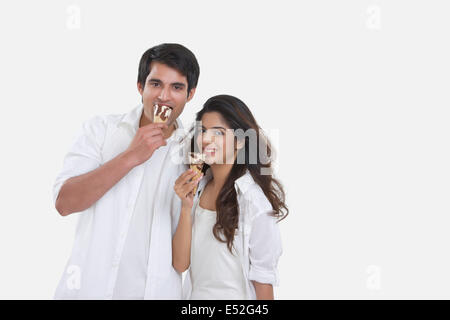 Portrait of happy young couple eating ice-cream cones isolé sur fond blanc Banque D'Images