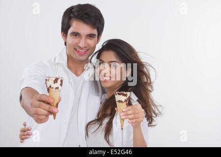 Portrait de jeune couple aimant montrant les cônes de glace sur fond blanc Banque D'Images