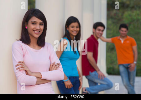 Portrait de femme heureuse et amis s'appuyant sur l'extérieur des colonnes Banque D'Images