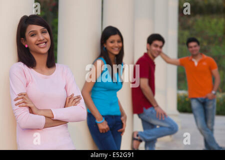 Portrait of smiling woman et amis s'appuyant sur l'extérieur des colonnes Banque D'Images