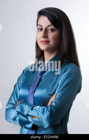 Portrait of Indian businesswoman standing arms crossed contre l'arrière-plan gris Banque D'Images