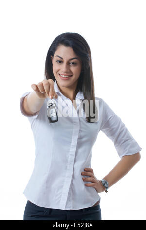 Smiling Indian businesswoman holding car keys against white background Banque D'Images