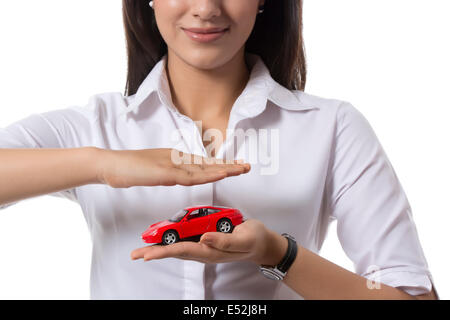 Portrait de jeune femme tenant un agent d'assurance voiture jouet contre fond blanc Banque D'Images