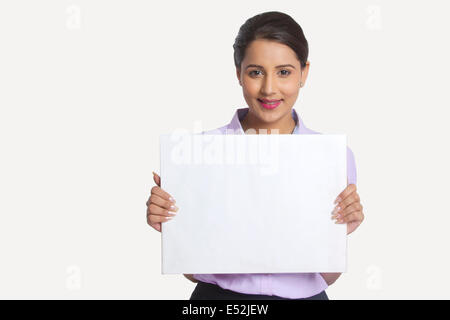 Portrait of businesswoman holding blank placard contre fond blanc Banque D'Images