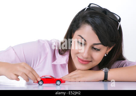 Businesswoman looking at petite voiture contre fond blanc Banque D'Images