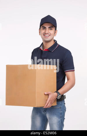 Portrait of handsome man carrying cardboard box against white background Banque D'Images